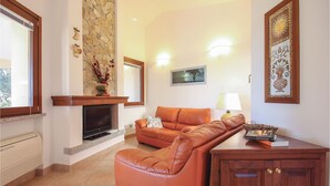 A living room with a stone fireplace, a sofa, a lamp, and a wooden cabinet.
