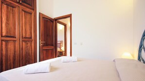 A hotel room with a bed, a nightstand, a mirror, and wooden wardrobes.