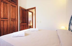 A hotel room with a bed, a nightstand, a mirror, and wooden wardrobes.
