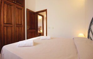 Een hotelkamer met een bed, een houten kledingkast en een spiegel die een lamp weerspiegelt.