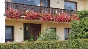 A building with a balcony adorned with hanging flower baskets. - Beautiful apartment in Schönecken (Schönecken)