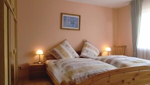 A double bed with patterned bedding, two bedside lamps, a framed picture on the wall, and a wooden headboard. - Beautiful apartment in Schönecken (Schönecken)