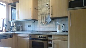 A kitchen with wooden cabinets, a stainless steel oven, a coffee maker, and a kettle. - Beautiful apartment in Schönecken (Schönecken)