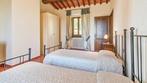A bedroom with two beds, a wooden ceiling, a radiator, and a window with curtains. - Awesome apartment in S. Giustino Valdarno with house a panoramic view (S. Giustino Valdarno)