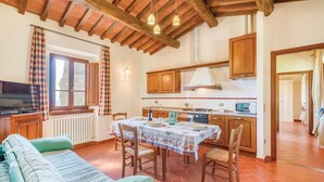 A cozy kitchen with wooden cabinets, a dining table set for four, and a television on a wooden stand. - Awesome apartment in S. Giustino Valdarno with house a panoramic view (S. Giustino Valdarno)
