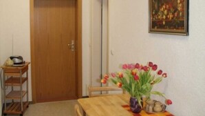 Un coin repas avec une table en bois, des chaises, un vase de tulipes et un tableau accroché au mur.