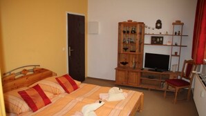 Une chambre à coucher avec un lit double, une armoire en bois avec des étagères, une télévision et une chaise.
