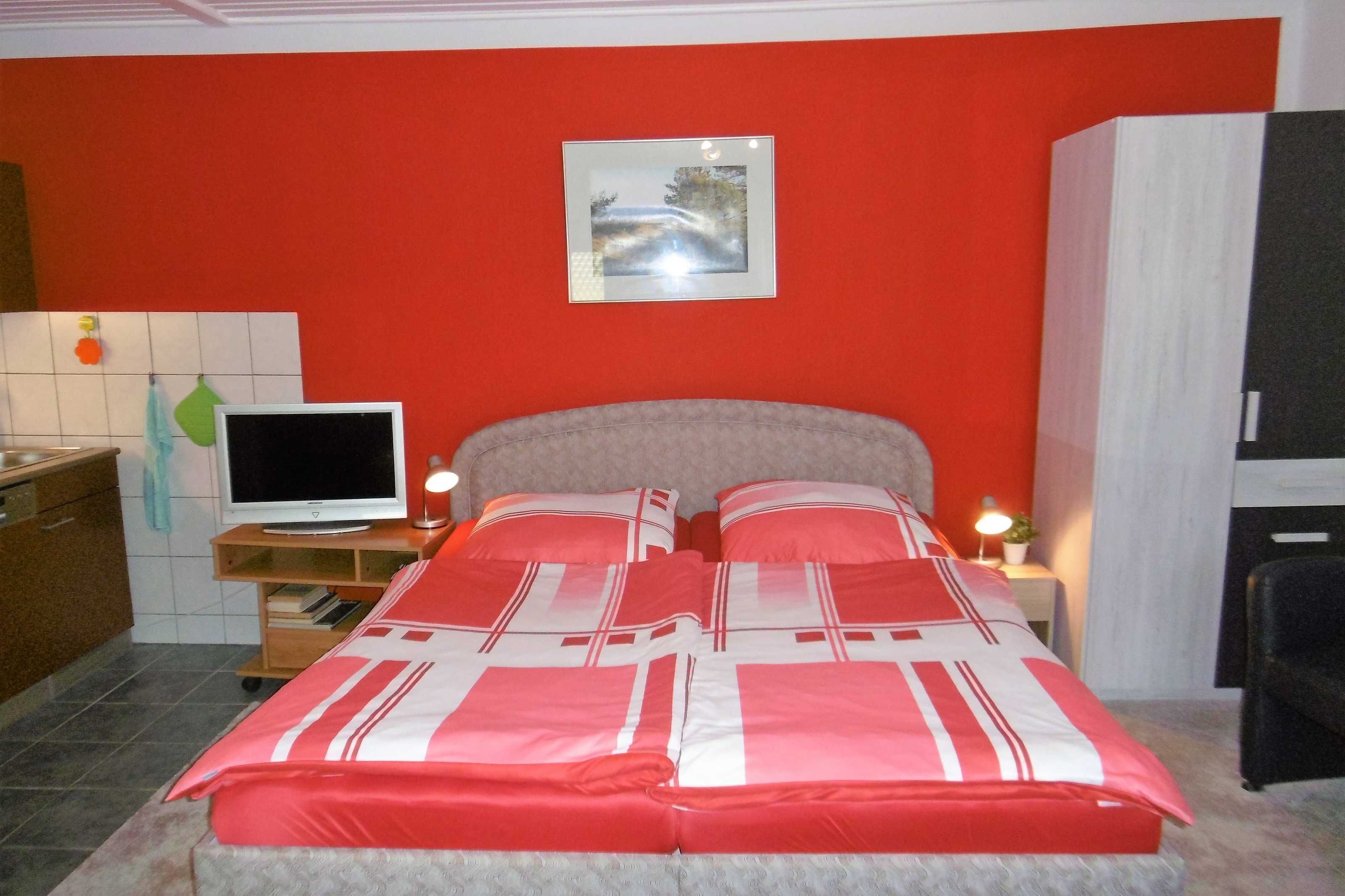 A bedroom with a bed, a TV, a desk, and a cabinet.