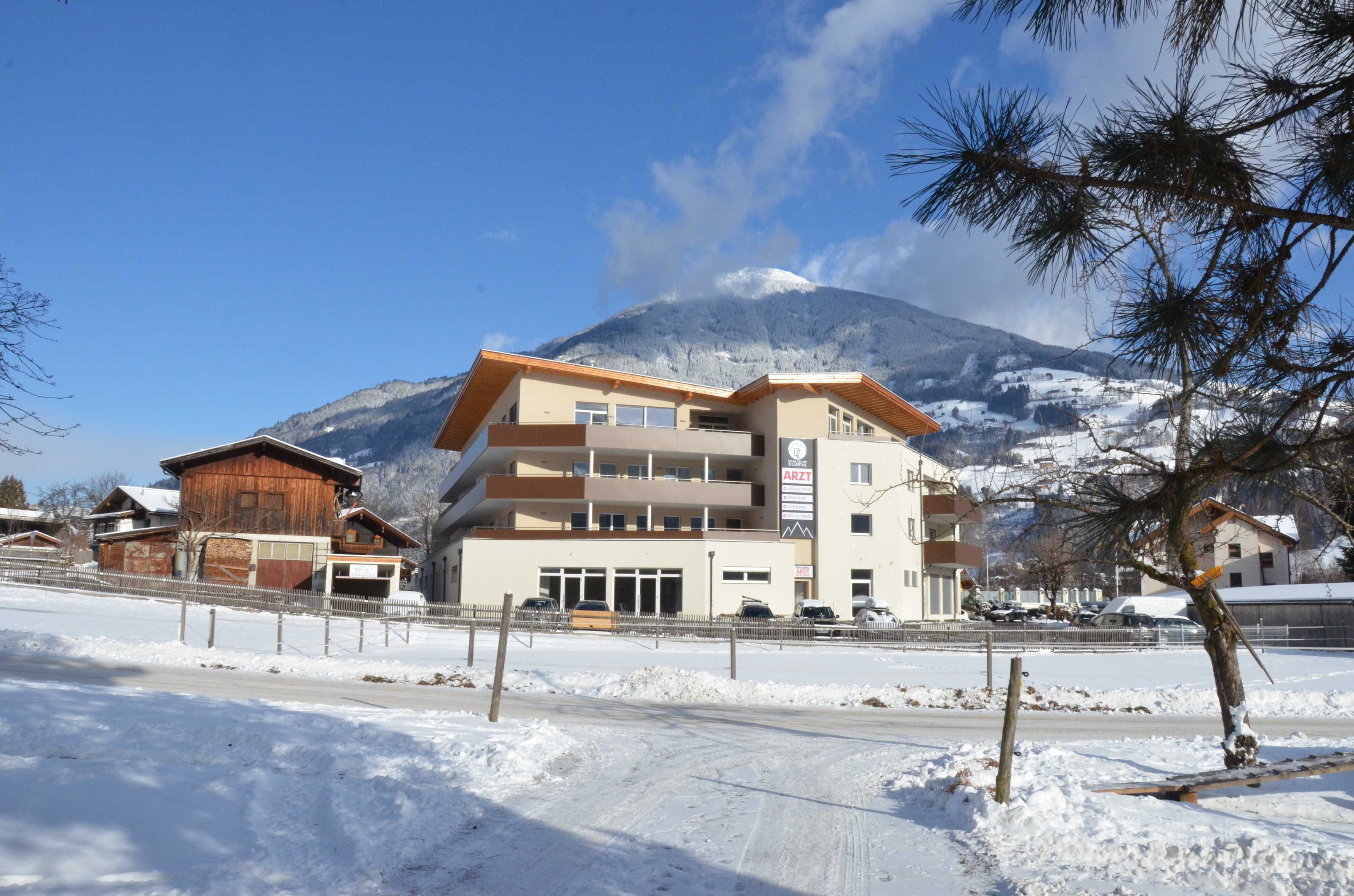 Un immeuble à plusieurs étages, avec une station de ski en arrière-plan.