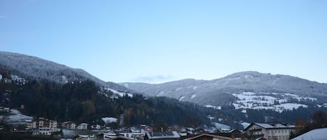 A residential area with buildings, a clear sky, and snow-covered mountains.