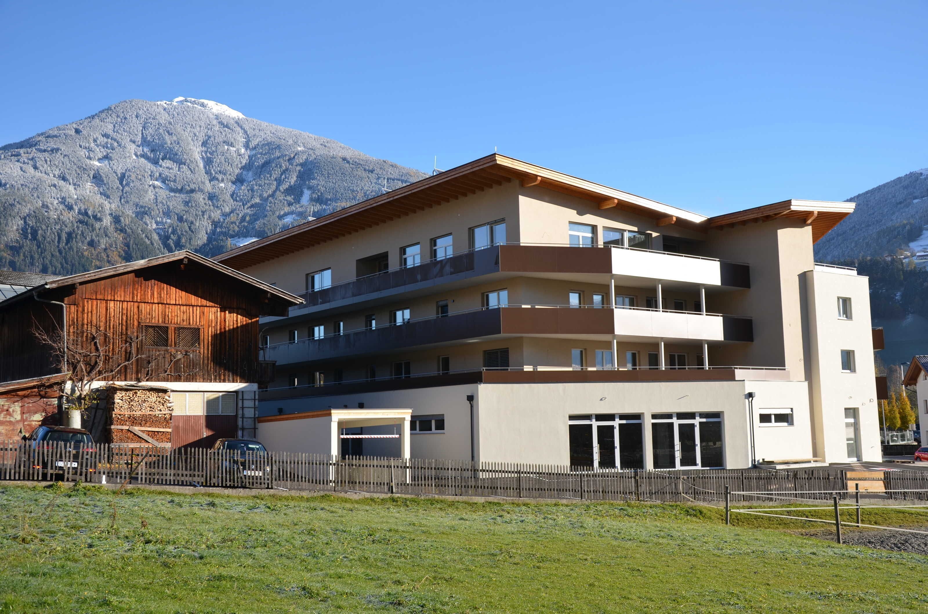 Ein mehrstöckiges Hotel mit Balkonen, einem Parkplatz und einem Blick auf die Berge.
