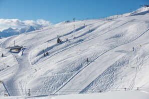 A snow-covered ski slope with ski lifts and a chairlift.