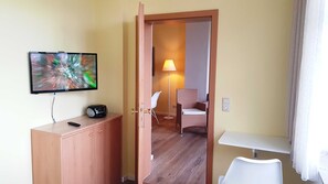 Hotellihuone, jossa on televisio, työpöytä, tuoli ja lamppu.
