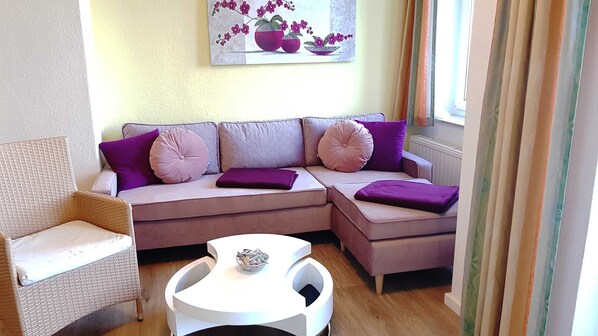A modern living room with a sectional sofa, a wicker chair, and a small white table.