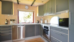 Une cuisine moderne dotée d’appareils électroménagers en acier inoxydable, de meubles de couleur grise et d’un plancher en bois.