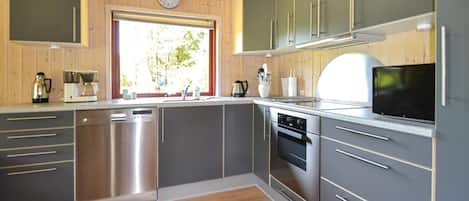 Une cuisine moderne dotée d’appareils électroménagers en acier inoxydable, de meubles de couleur grise et d’un plancher en bois.