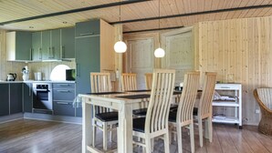 Une cuisine moderne avec des meubles en bois, une table à manger avec des chaises, des luminaires suspendus et un plancher en bois.