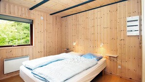 Une chambre avec un lit, une fenêtre, un radiateur fixé au mur et une prise électrique.