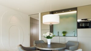 A modern dining area with a round table, six grey upholstered chairs, a white vase with flowers, and a pendant light. - K6 from A&M - K6, Germany (Kampen (Sylt))