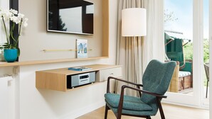 A modern living room with a flat-screen TV, a bookshelf, a potted plant, and a view of the outdoors. - K6 from A&M - K6, Germany (Kampen (Sylt))