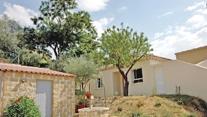 Ein Steinhaus mit Ziegeldach, ein kleiner Garten mit Baum und ein Steinbrunnen.