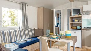 A compact kitchen with a dining area, a window with curtains, and a kitchenette.