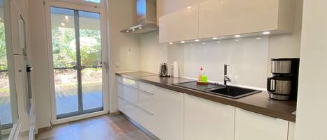 A modern kitchen with white cabinets, a stainless steel sink, and a coffee maker.