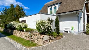 Ein modernes Haus mit einer Steinwand, einem Strohdach und einer gepflasterten Auffahrt.
