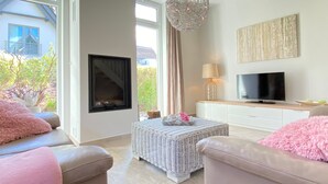 Ein Wohnzimmer mit Kamin, Fernseher und Korbmöbeln.