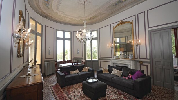 Ein Zimmer mit zwei Sofas, einer Kandelaber und einem großen Spiegel.