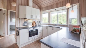 Eine moderne Küche mit weißen Schränken, einem Bosch-Ofen und einem großen Fenster, das für natürliches Licht sorgt.