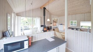 Ein gemütliches Blockhauss-Interieur mit Küchenzeile, Esstisch und großem Fenster für natürliches Licht.