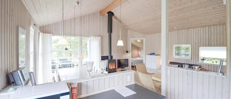 A cozy cabin interior with a kitchen area, a dining table, and a large window providing natural light.