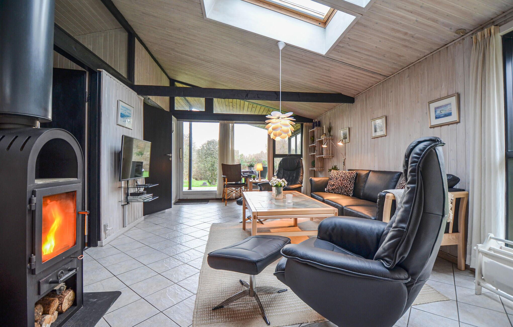 Ein modernes Wohnzimmer mit Kamin, Ledermöbeln und einem Oberlicht.