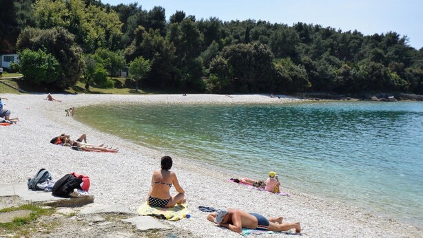 A beach with people sunbathing and swimming. - Holiday apartment with terrace and air conditioning (Pula)