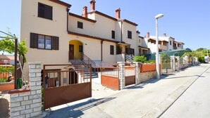 A multi-story residential building with a beige facade, dark shutters, and a central entrance with steps. - Holiday apartment with terrace and air conditioning (Pula)