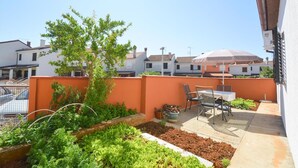A rooftop garden with a dining area, a tree, and a view of neighboring buildings. - Holiday apartment with terrace and air conditioning (Pula)