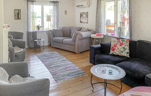 A living room with a sofa, armchairs, a coffee table, and a rug.