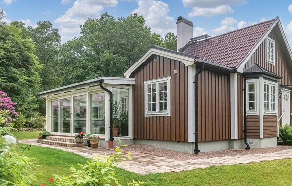 A two-story house with a conservatory, a chimney, and a garden with potted plants. - Nice home in Halmstad with kitchen (Halmstad)