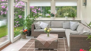 Ein Wintergarten mit einer Couch, einem Couchtisch und Topfpflanzen.