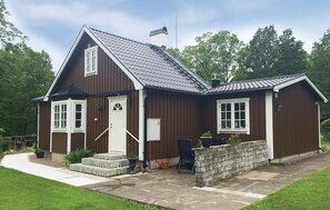 A two-story wooden house with a steep gable roof, a front porch with steps, and a brick wall. - Nice home in Halmstad with kitchen (Halmstad)