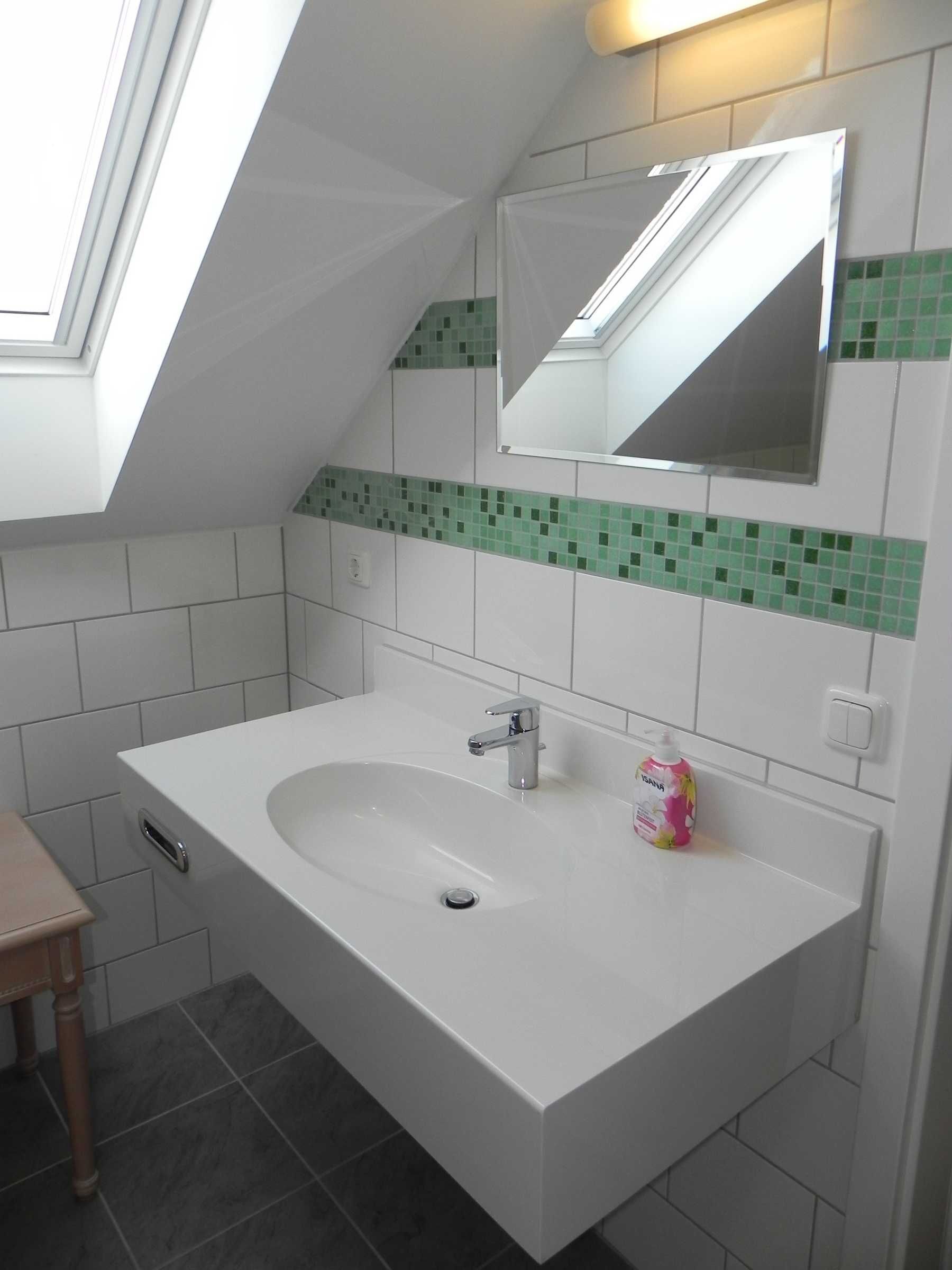 A modern bathroom with a skylight, a large sink, and a mirror.