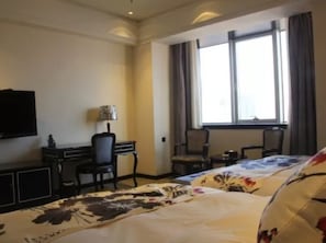 Una habitación de hotel con cama, escritorio, silla y televisión.