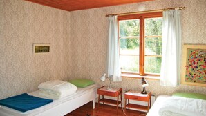 A bedroom with two beds, a window with curtains, a bedside table with a lamp, and a patterned wall. - 2 bedroom cozy home in Hamneda (Hamneda)