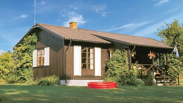 A wooden house with a sloped roof, a chimney, and a porch with a flag. - 2 bedroom cozy home in Hamneda (Hamneda)