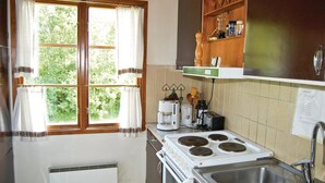 A kitchen with a stove, sink, and window with curtains. - 2 bedroom cozy home in Hamneda (Hamneda)