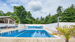 Ein Schwimmbecken mit klarem, blauem Wasser, umgeben von einer weißen Mauer und einer Holzterrasse.