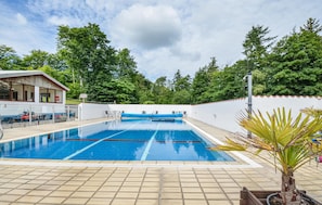 Una piscina con acqua cristallina blu, circondata da un muro bianco e un pontile in legno.