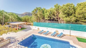 Une piscine dont le design est inspiré d’un cadran solaire, entourée de chaises longues et d’un patio couvert.