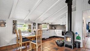 A kitchen with white cabinets, a black stove, and a dining area with wooden chairs and a table.
